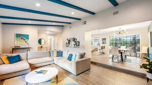 A modern living room with a sectional sofa, a coffee table, and artwork on the walls. - Upscale private paradise on large dog-friendly lot w/ free EV charger (Palm Springs)