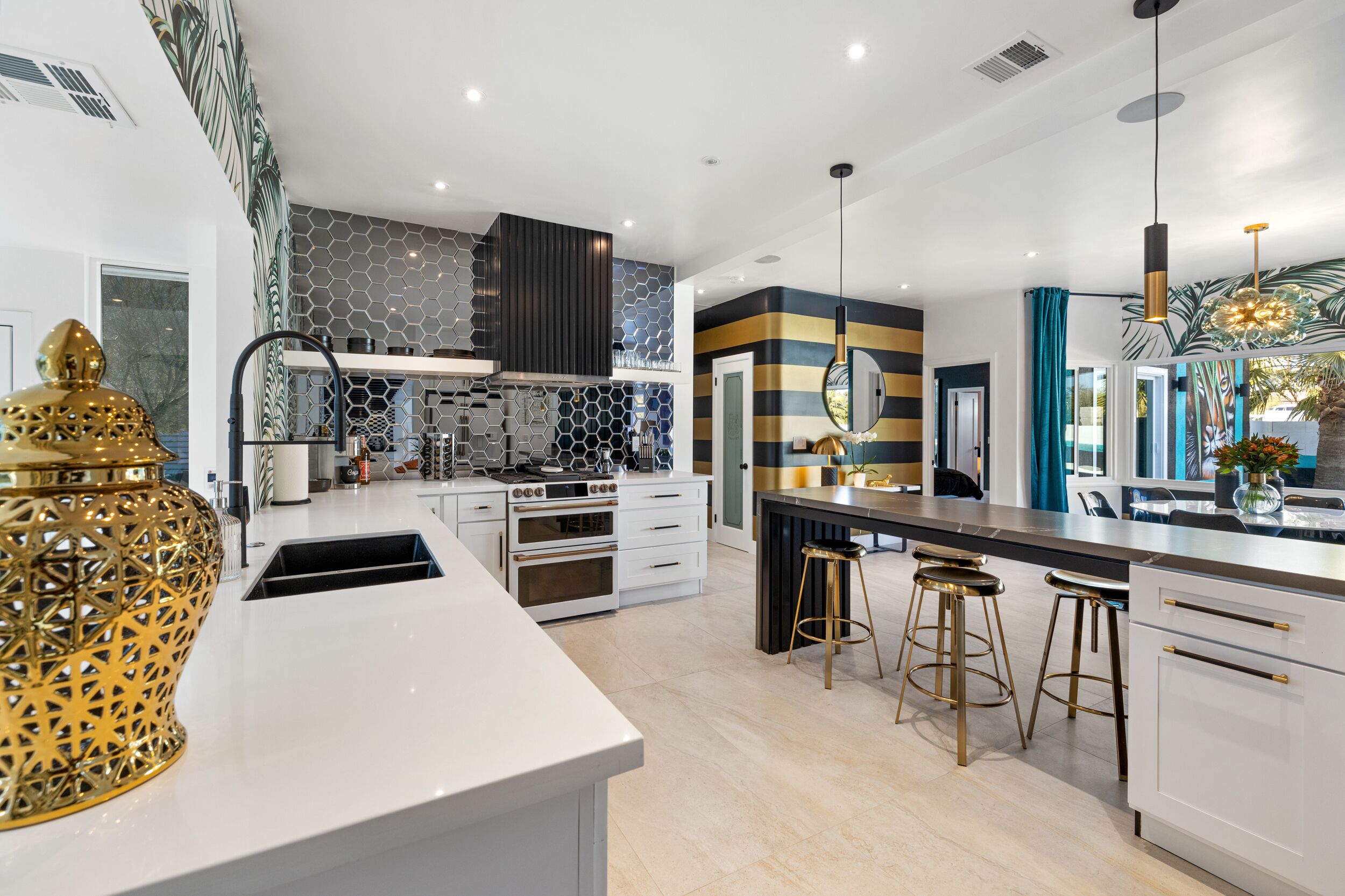 Une cuisine moderne avec des meubles blancs, un îlot central et un vase décoratif doré.