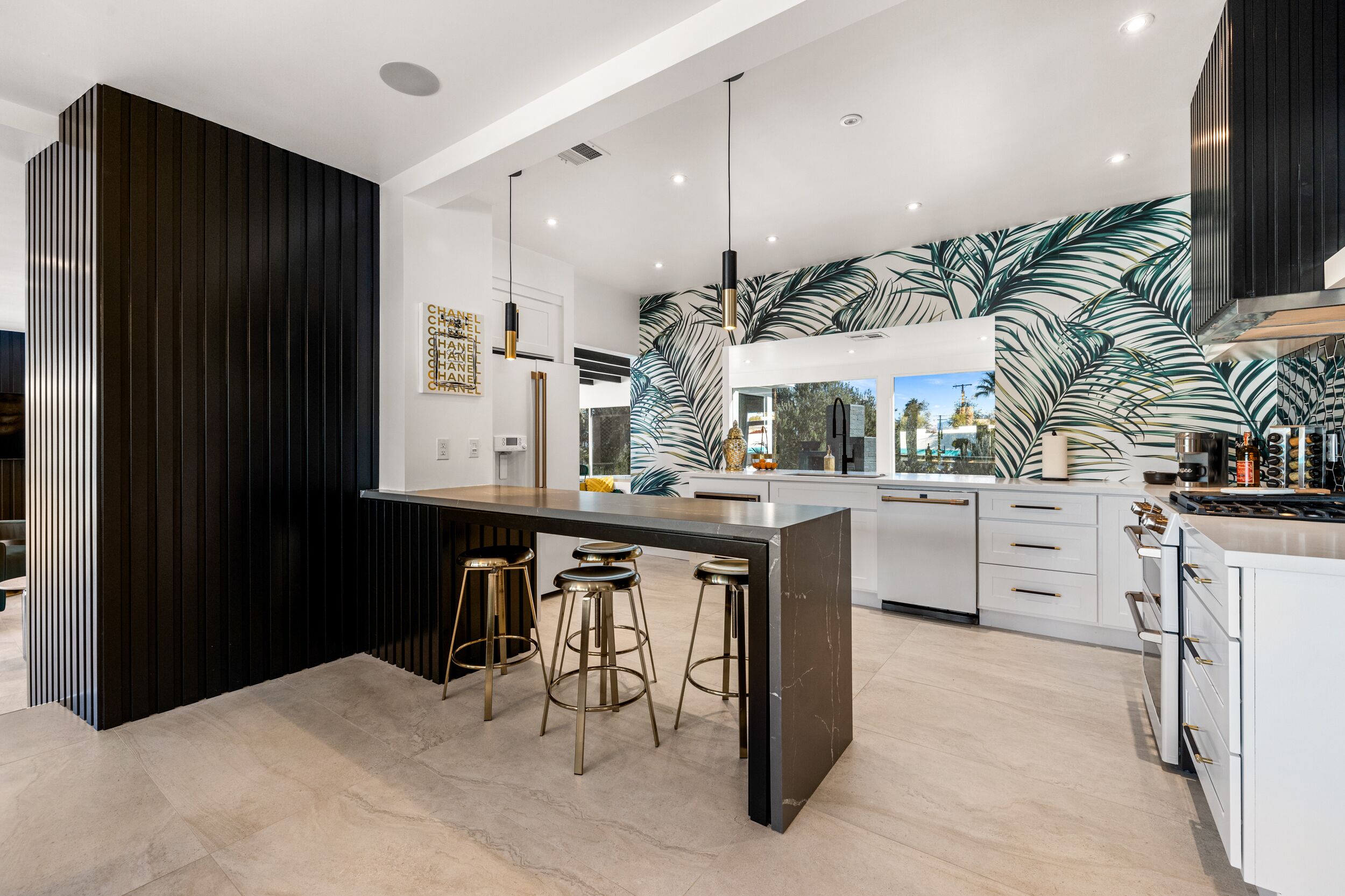 Una cocina moderna con una isla central, taburetes de bar y un amplio ventanal.
