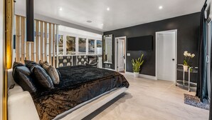 Een moderne slaapkamer met een groot bed, een televisie en uitzicht op de omgeving.