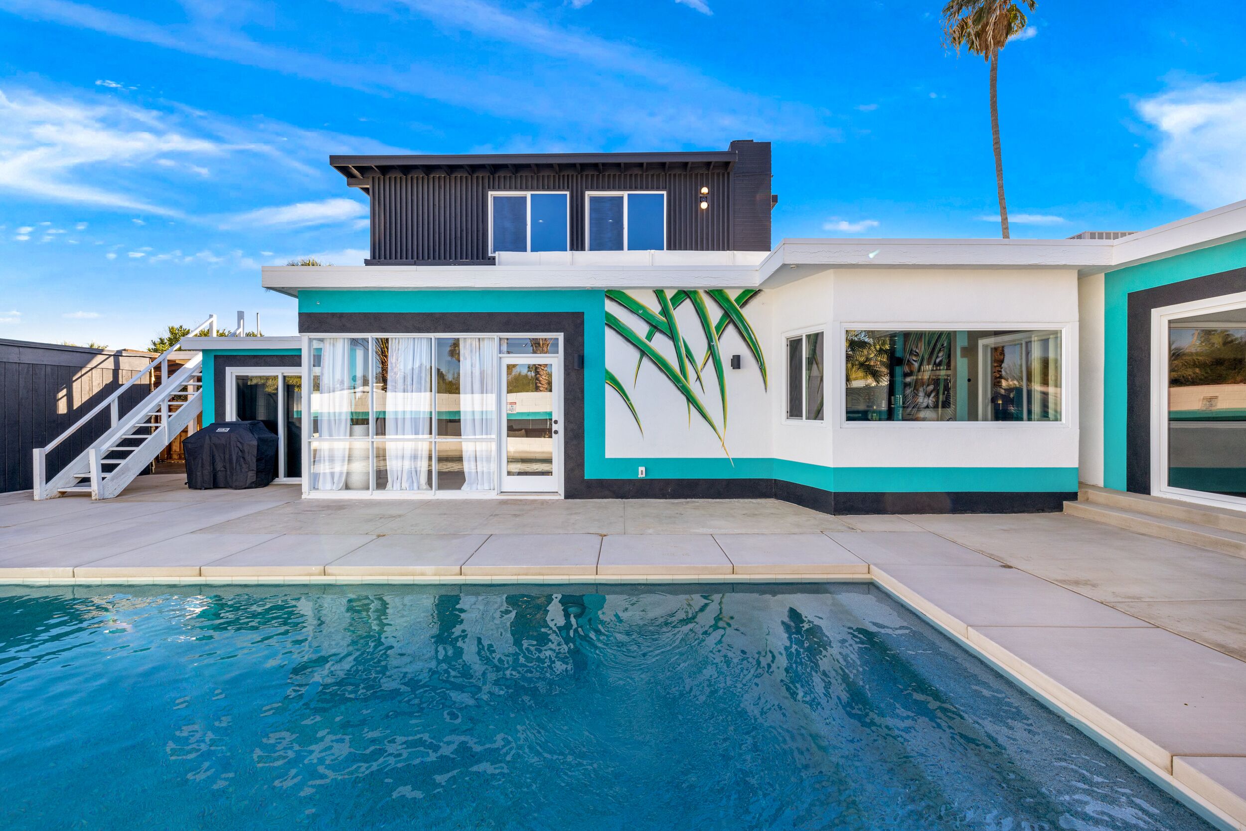 A modern two-story house with a swimming pool, large windows, and a staircase leading to the upper level.