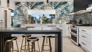Een moderne keuken met een groot eiland, barstoelen en uitzicht op de omgeving.