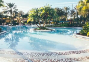 Relax by the serene pool surrounded by lush tropical vegetation and lounge chairs.