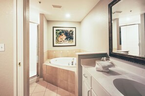 Bathroom features a large bathtub, sink, and mirror, with a framed picture on the wall.