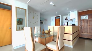 Een moderne keuken met een glazen eettafel, houten stoelen en een houten kast.