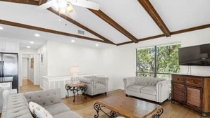 Un salon spacieux comprenant un grand canapé, une table basse en bois et un téléviseur.