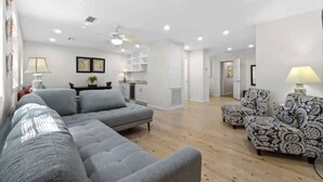 Un salon moderne avec un canapé gris, des fauteuils à motifs et un plancher en bois.