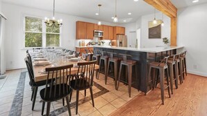 Una cocina moderna con armarios de madera, una isla central, taburetes de bar e iluminación colgante.