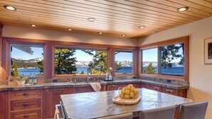 Une cuisine dotée d’un grand îlot central, de meubles en bois et offrant une vue sur la mer.