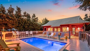 Une piscine avec des chaises longues et un espace abrité avec un bâtiment rouge.