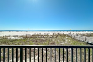 A beach view with a wooden boardwalk and a sandy beach.