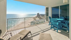 A balcony with a view of the beach and ocean, furnished with lounge chairs and a table. - Palacio 1703 | Stunning Gulf Views | My Beach Getaways (Pensacola)