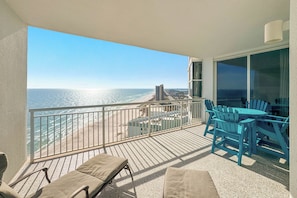 A balcony with a view of the beach and ocean, furnished with lounge chairs and a table. - Palacio 1703 | Stunning Gulf Views | My Beach Getaways (Pensacola)