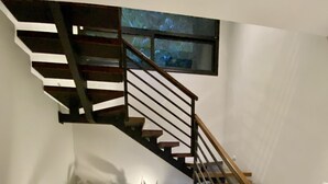 A modern staircase with wooden steps and metal railings, leading to a landing with a small window. - Outstanding High End Luxury, Most Convenient Location and World Class Ocean View (Uvita)