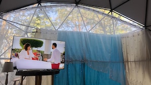 Uma tenda com uma tela de televisão exibindo uma cena de casamento.