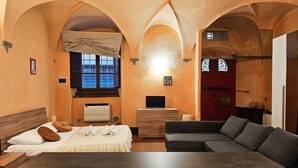 Una habitación con cama, sofá, televisión, ventana y puerta.