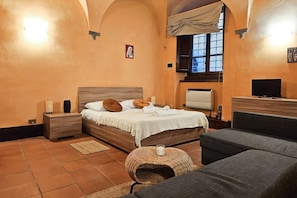 Ein Schlafzimmer mit Bett, Nachttischen, einem Fernseher und einer Couch.