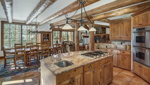 Una cocina rústica con vigas de madera, una isla grande con un lavamanos y electrodomésticos integrados.