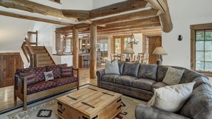 Amplia sala de estar con una escalera de madera, un conjunto de sofás, un sofá de cuero y una mesa de centro de madera.