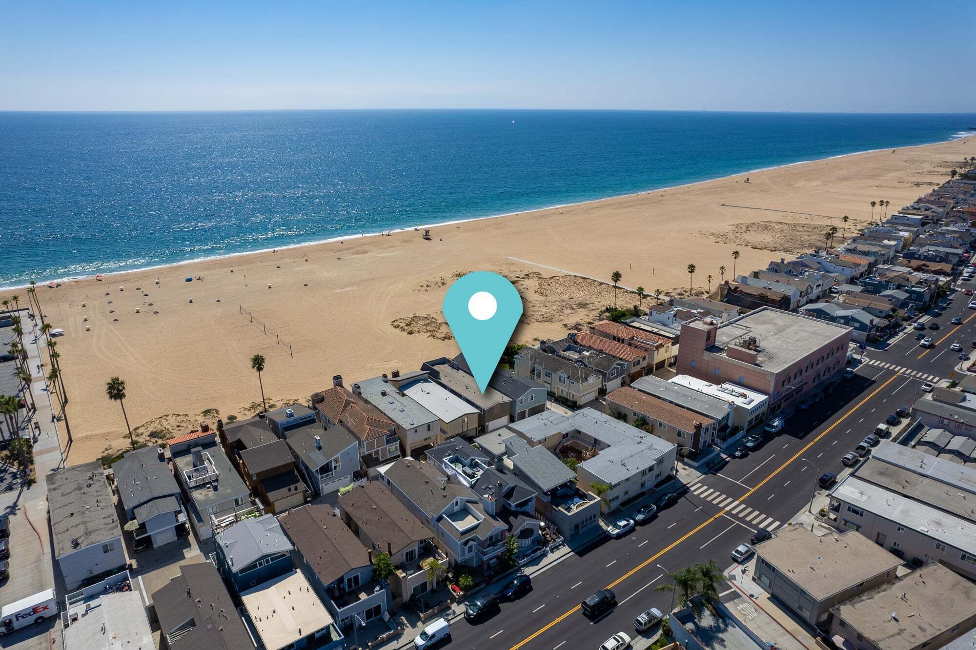 Vista aérea de un pueblo costero con playa, edificios residenciales y una carretera.