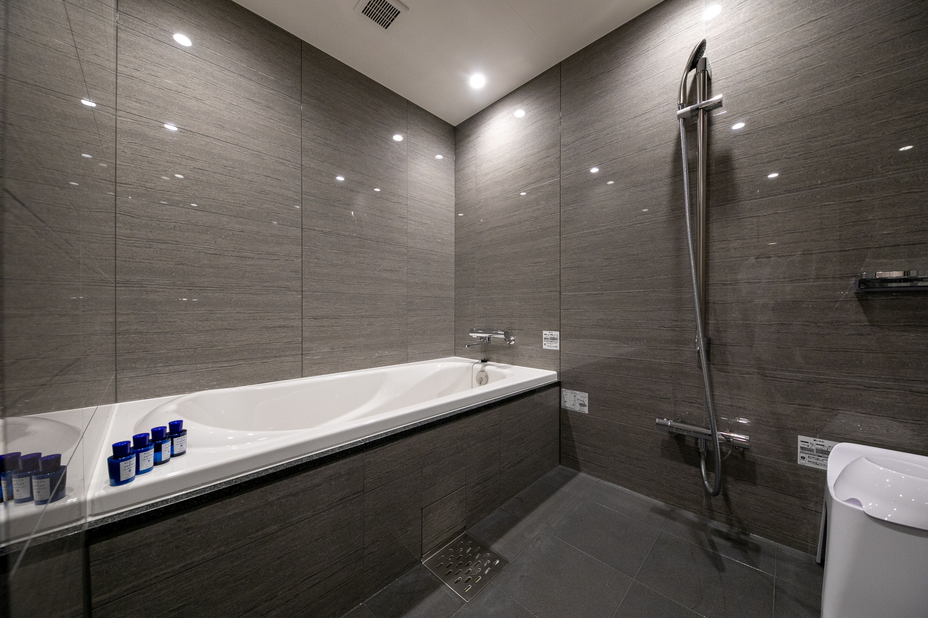 Un baño moderno con una bañera grande, ducha y tocador con artículos de aseo.