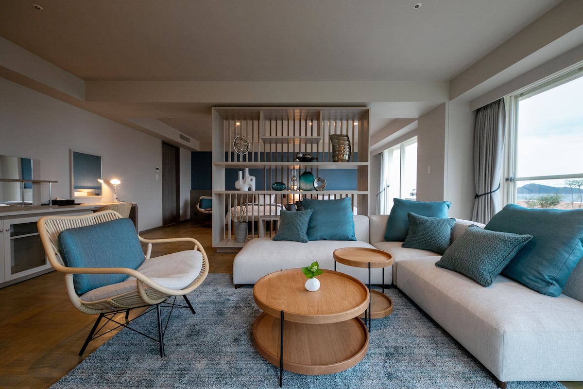 A modern living room with a sofa, chairs, a coffee table, and a bookshelf.