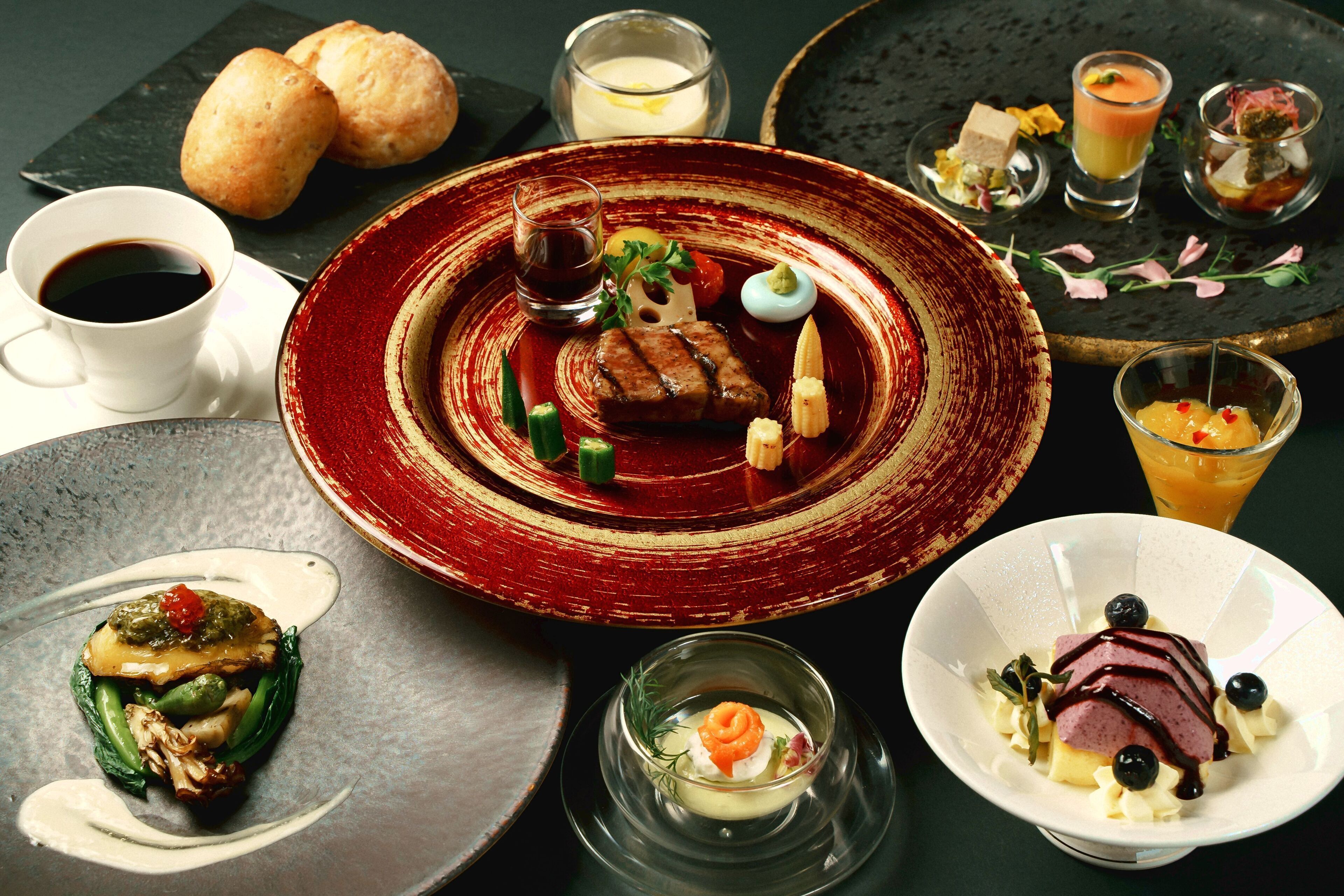 A variety of dishes on a dining table, including a plate with a steak, a glass of juice, and several small plates with different foods.