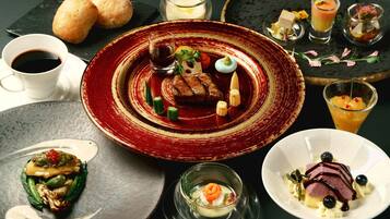 A variety of dishes on a dining table, including a plate with a steak, a glass of juice, and several small plates with different foods.