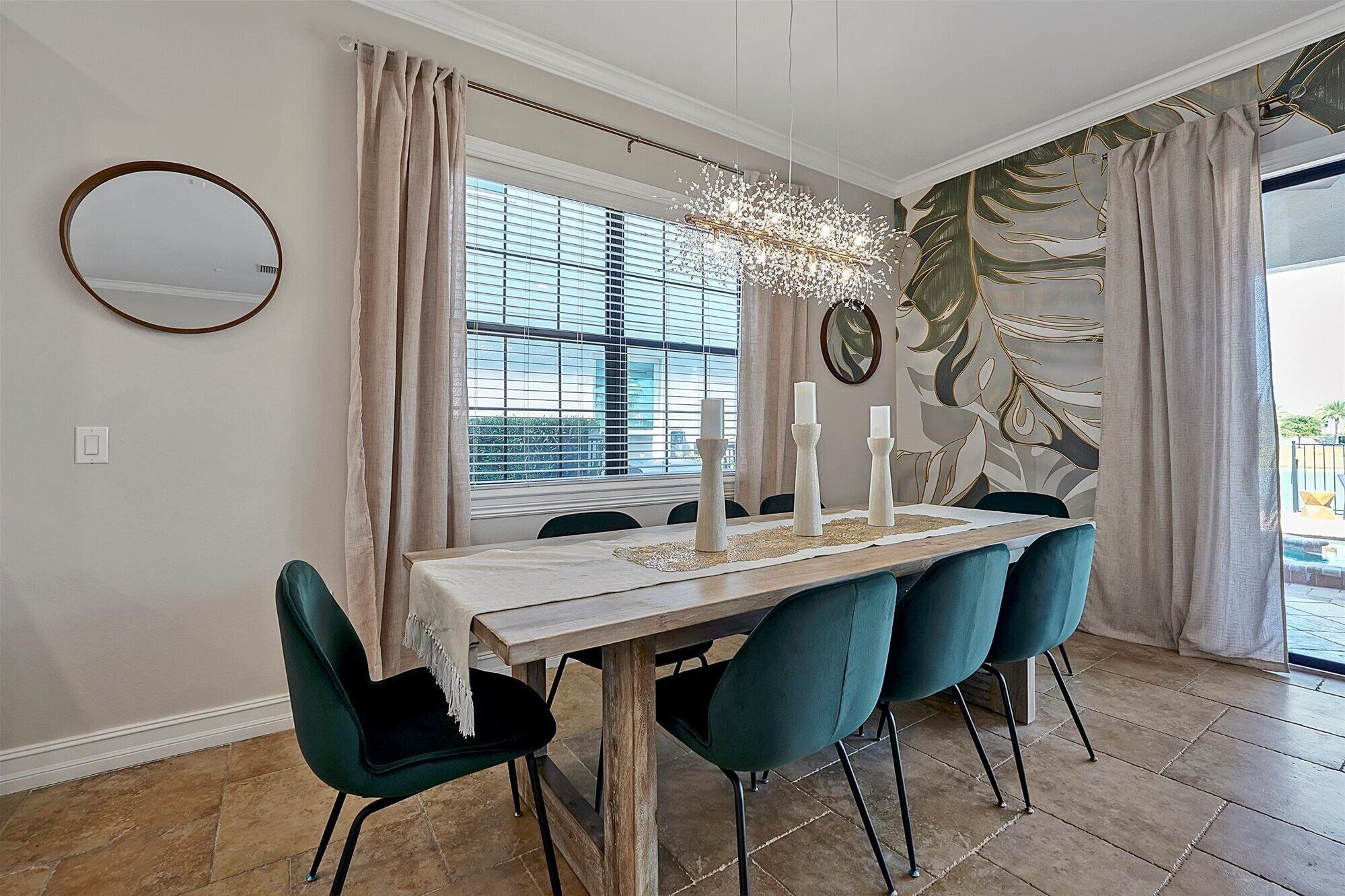 A dining area with a wooden table, teal chairs, and a chandelier.