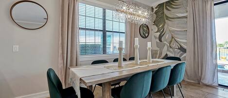 A dining area with a wooden table, teal chairs, and a chandelier.