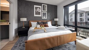 A modern bedroom with a bed, bedside tables, a ceiling fan, and large windows.