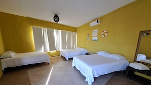 Quarto de hotel com duas camas de solteiro, um espelho grande e um ventilador de teto.