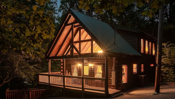 Une cabane en bois dotée d’un balcon, de grandes fenêtres et d’un toit en métal.