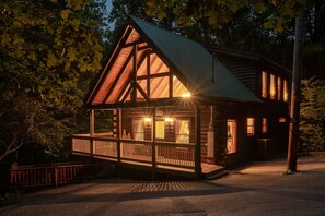 Une cabane en bois dotée d’un balcon, de grandes fenêtres et d’un toit en métal.
