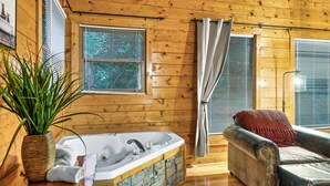 L'intérieur d'un chalet en bois, avec une baignoire, un canapé et une plante en pot.