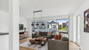 Een ruime woonkamer met een bank, salontafel en een televisie op een houten kast.