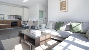 A modern living room with a sofa, coffee table, and a dining area with chairs. - Serene St Johns Wood 2BR, nr Park & Universities, by Blueground (London)
