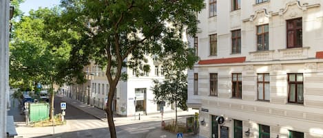 Une vue de rue avec un bâtiment devant lequel se trouve un grand arbre, un passage piéton et un panneau indiquant « Gass ».