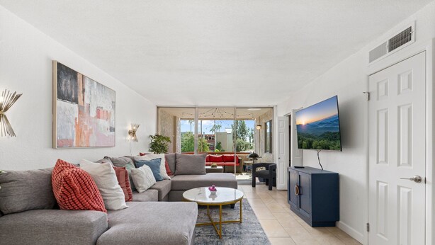 A modern living room with a grey sectional sofa, a coffee table, and a TV mounted on the wall. - Maya Motel (Scottsdale)
