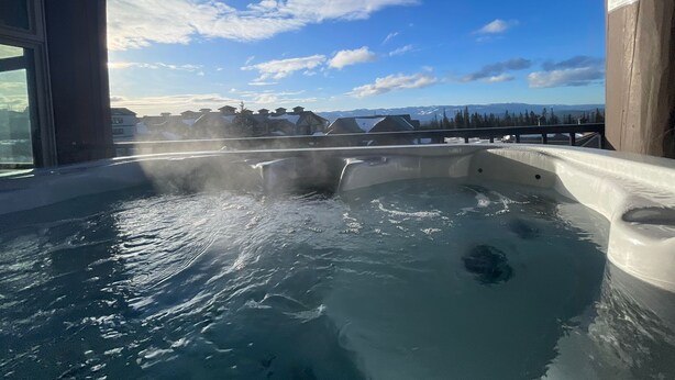 A hot tub with a view of mountains and a clear sky.
