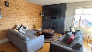 A living room with two sofas, a wooden wall, a fireplace, and a TV.