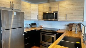 A modern kitchen with stainless steel appliances, wooden cabinets, and a black countertop.