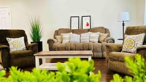 Un salon avec deux fauteuils marron, une table basse en bois et une grande plante en pot.