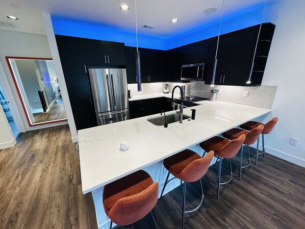 Una cocina moderna con una isla central, electrodomésticos de acero inoxidable y una decoración en blanco y negro.