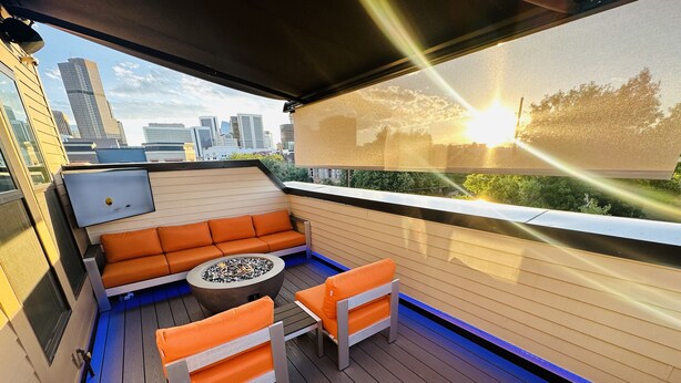 Una terraza en la azotea con zona de estar, un hogar para fuego y vistas del horizonte de la ciudad.