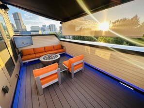 Una terraza en la azotea con zona de estar, un hogar para fuego y vistas del horizonte de la ciudad.