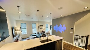 Una cocina moderna con una isla central, electrodomésticos integrados y un comedor con sofá y mesa.