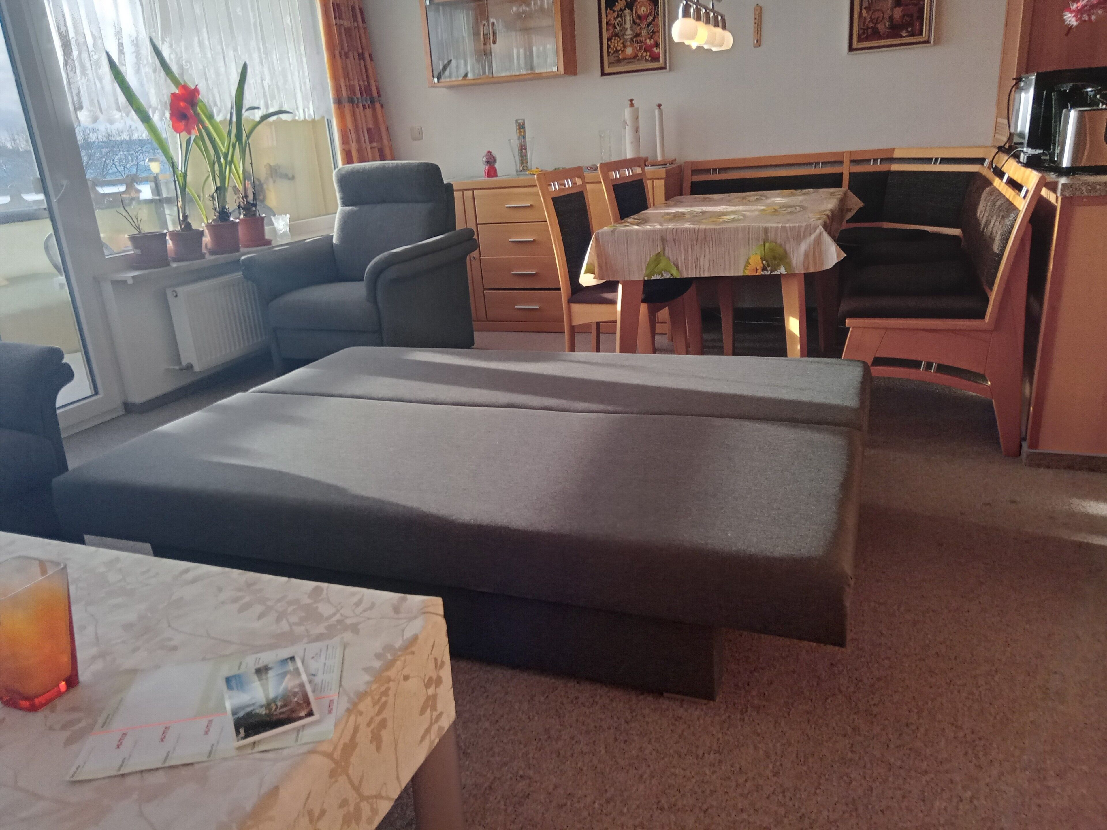 Une pièce comprenant un canapé-lit, une table à manger, des chaises, un petit coin cuisine et une fenêtre avec des rideaux.