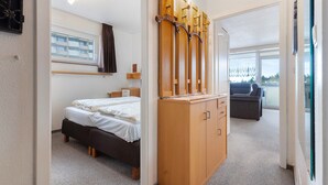 Une chambre à coucher avec un lit, une armoire en bois, une fenêtre avec des rideaux et un balcon offrant une vue.