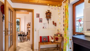 Una habitación acogedora con un banco de madera, un reloj, un radiador y una ventana con cortinas.